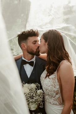 A bride and groom kissing under a veil