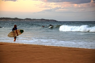 A person walking on a beach with a surfboard
