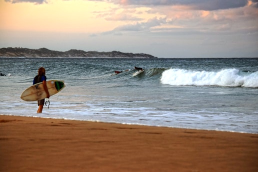 A person walking on a beach with a surfboard