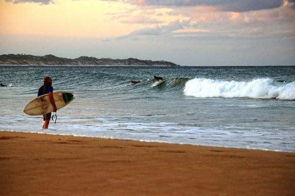 A surfer walking out at sunset — Tofo, Mozambique