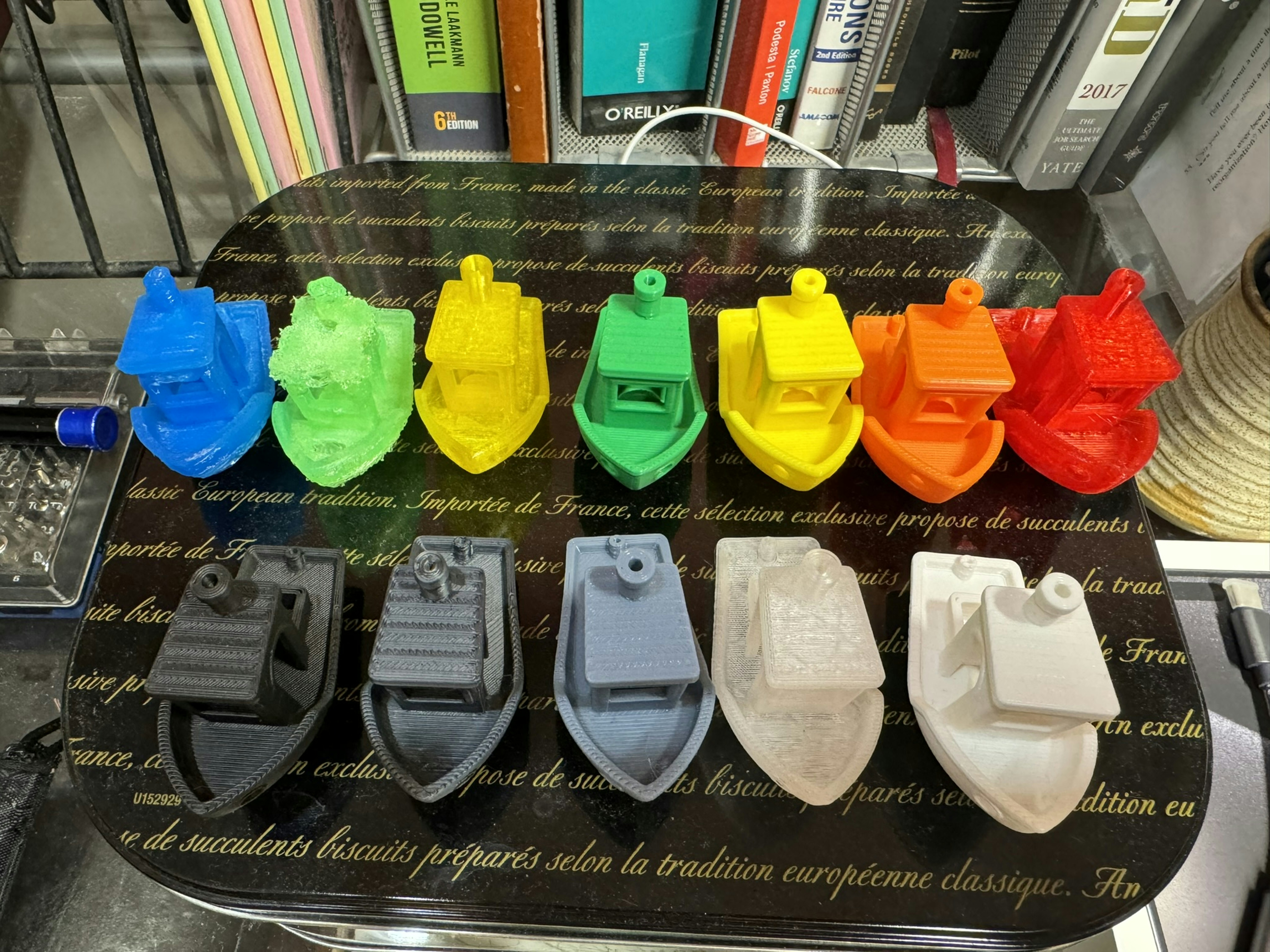 Collection of colorful 3D printed objects arranged on dark surface, moody low-key lighting