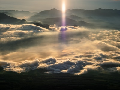 The sun is shining above the clouds in the sky