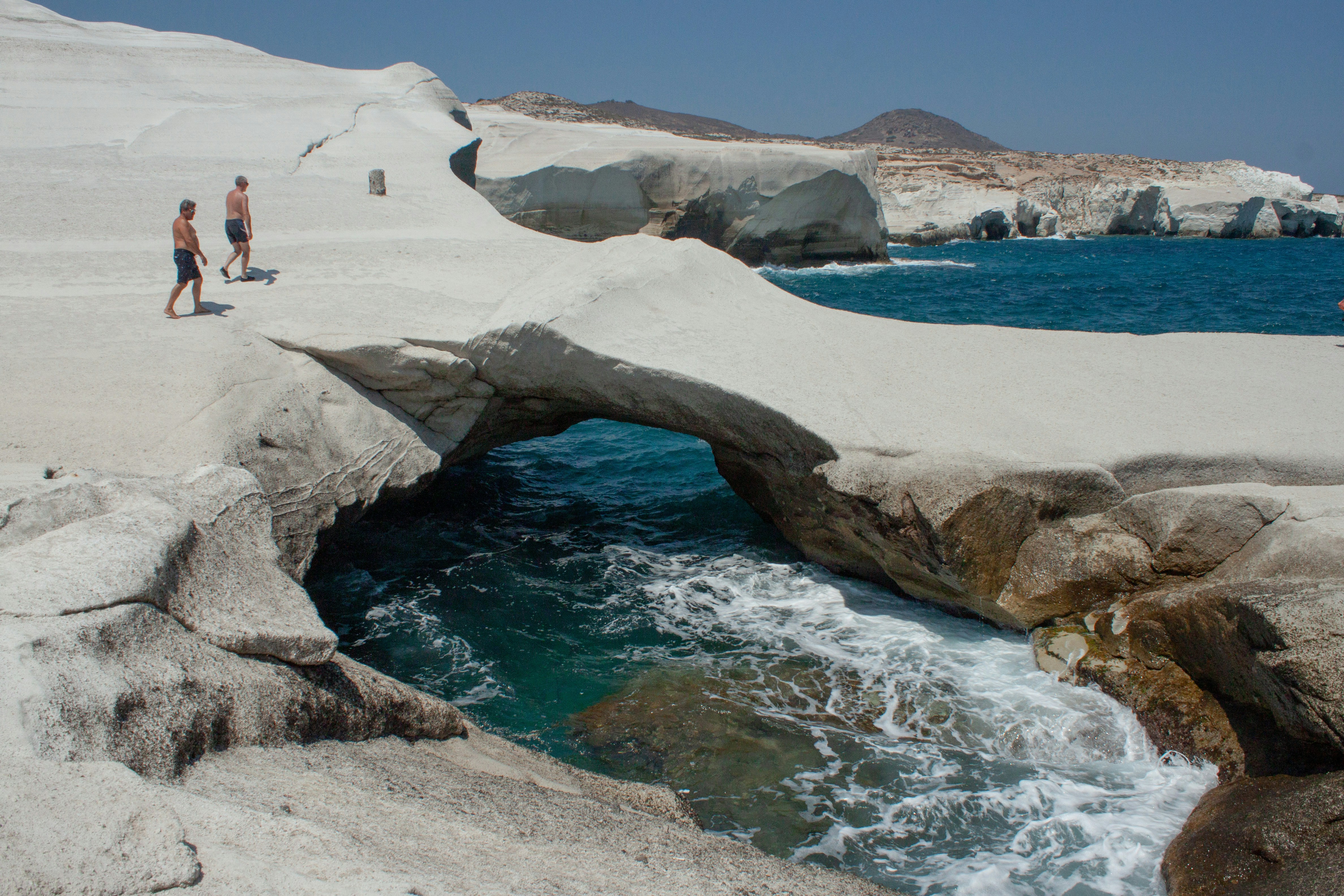 A couple of people walking across a bridge over a body of water