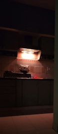 A kitchen with a stove top oven sitting under a light