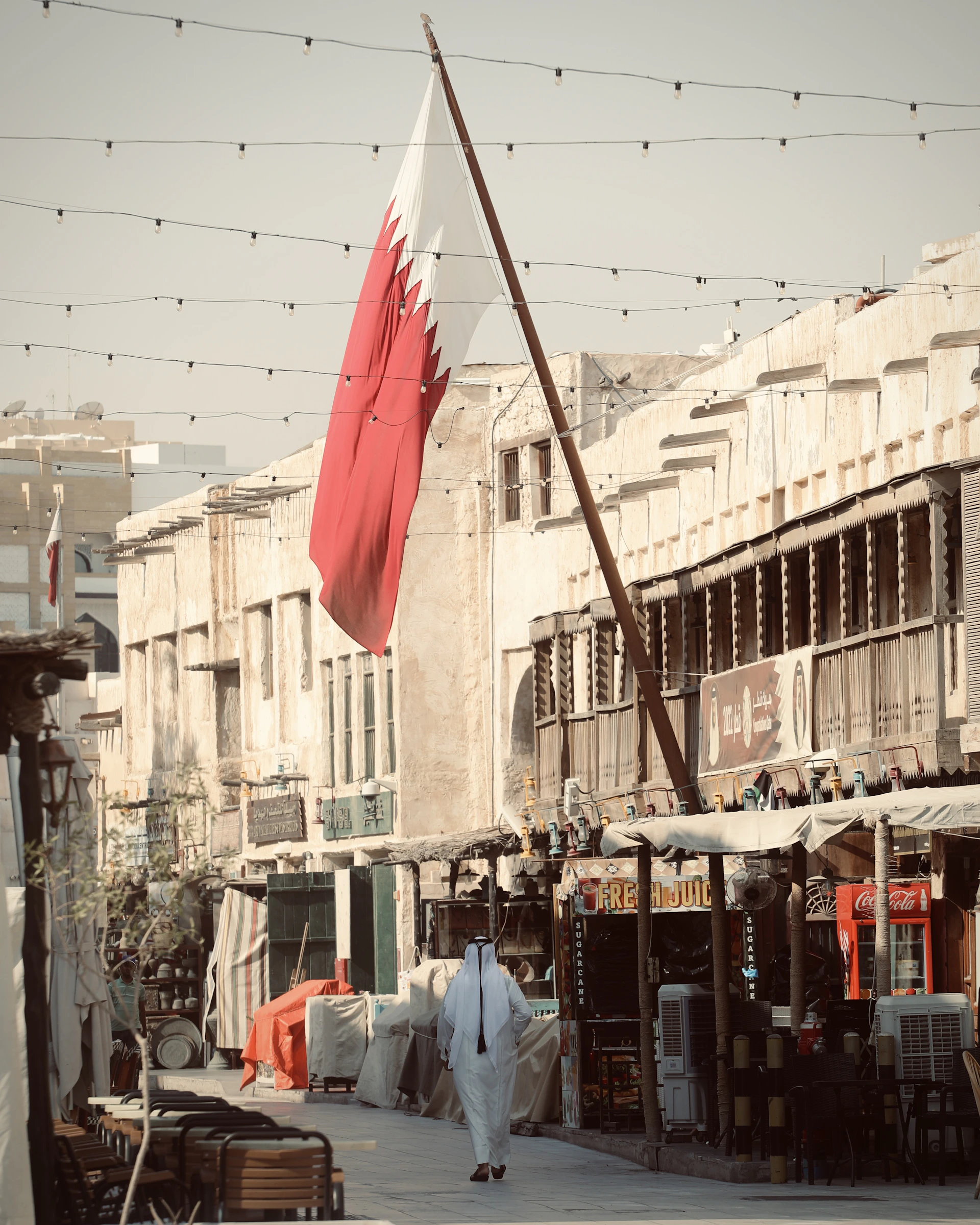 A man walking down a street next to a flag