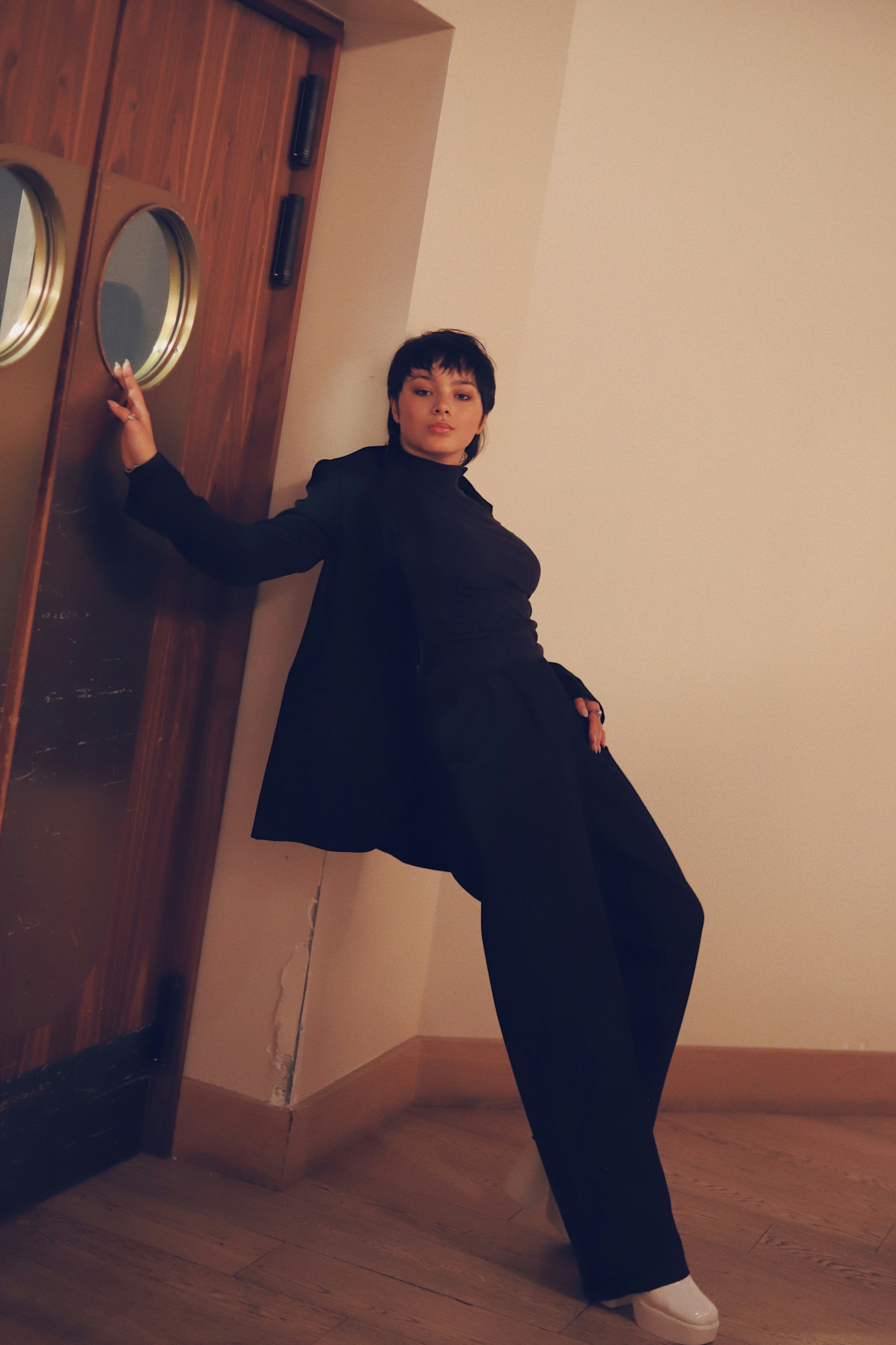 ドアにもたれかかっている黒いコートを着た女性