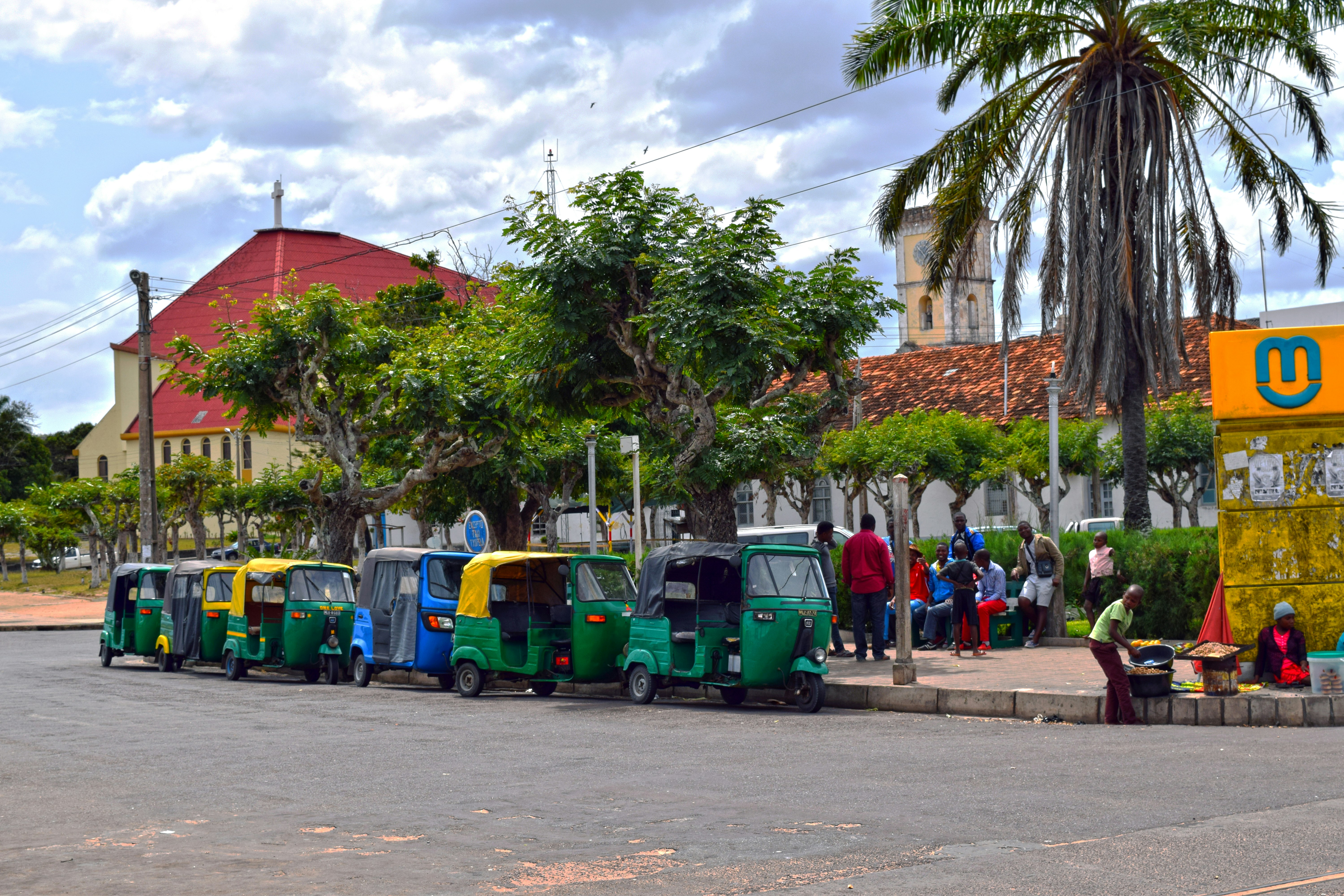 A group of people standing next to a row of parked vespas