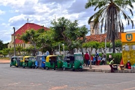 A group of people standing next to a row of parked vespas