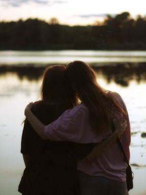 A couple of people standing next to each other near a body of water