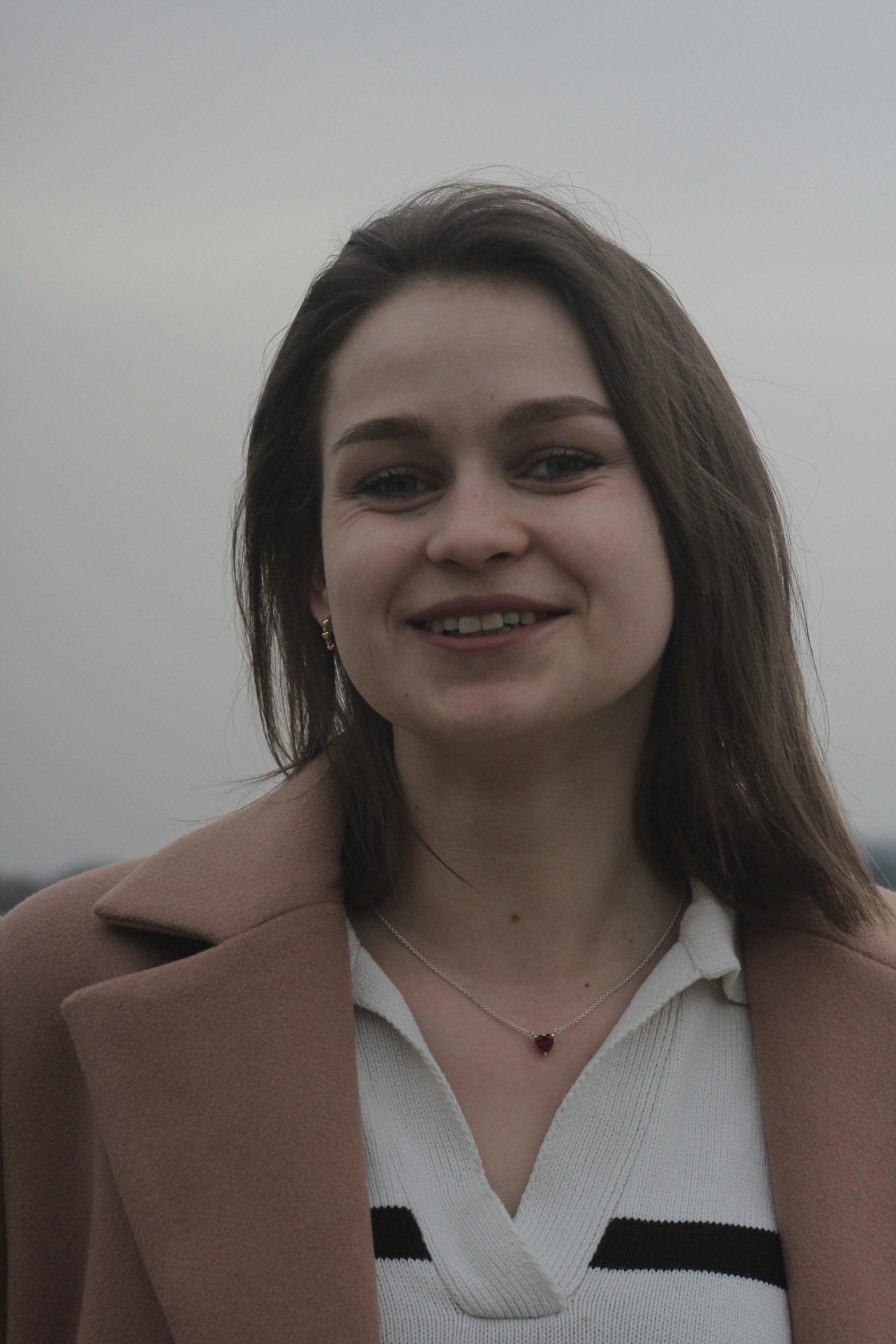 A woman standing in front of the ocean smiling