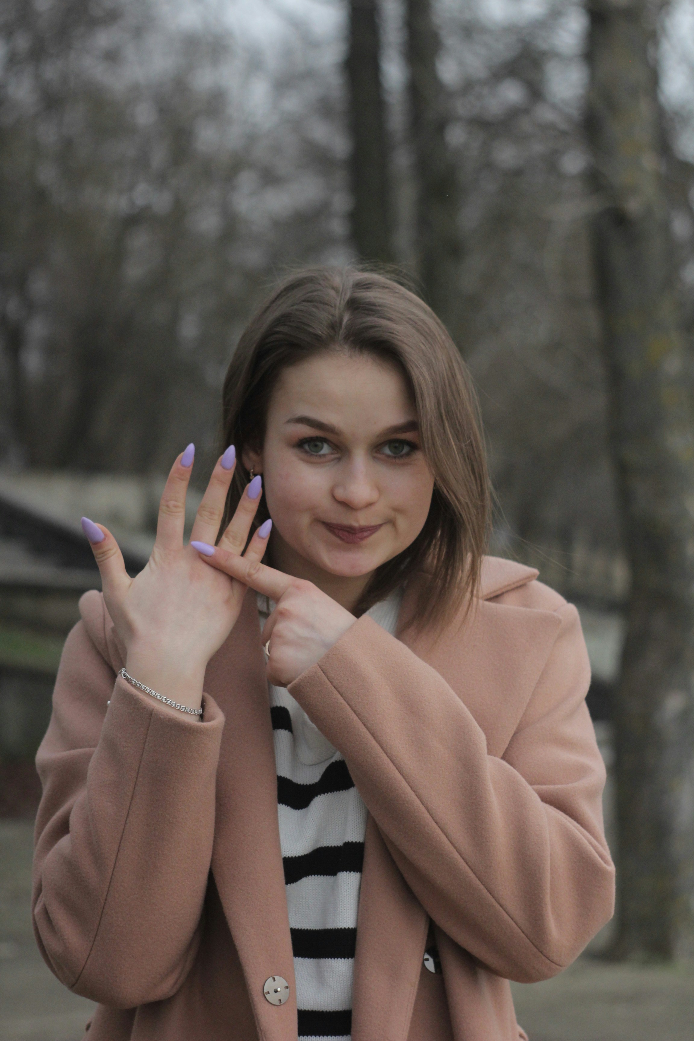 A woman in a pink coat is holding her hand up