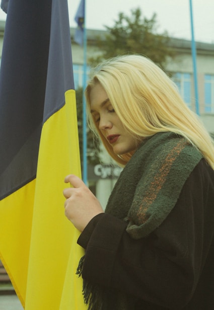 A blonde woman holding a black and yellow flag
