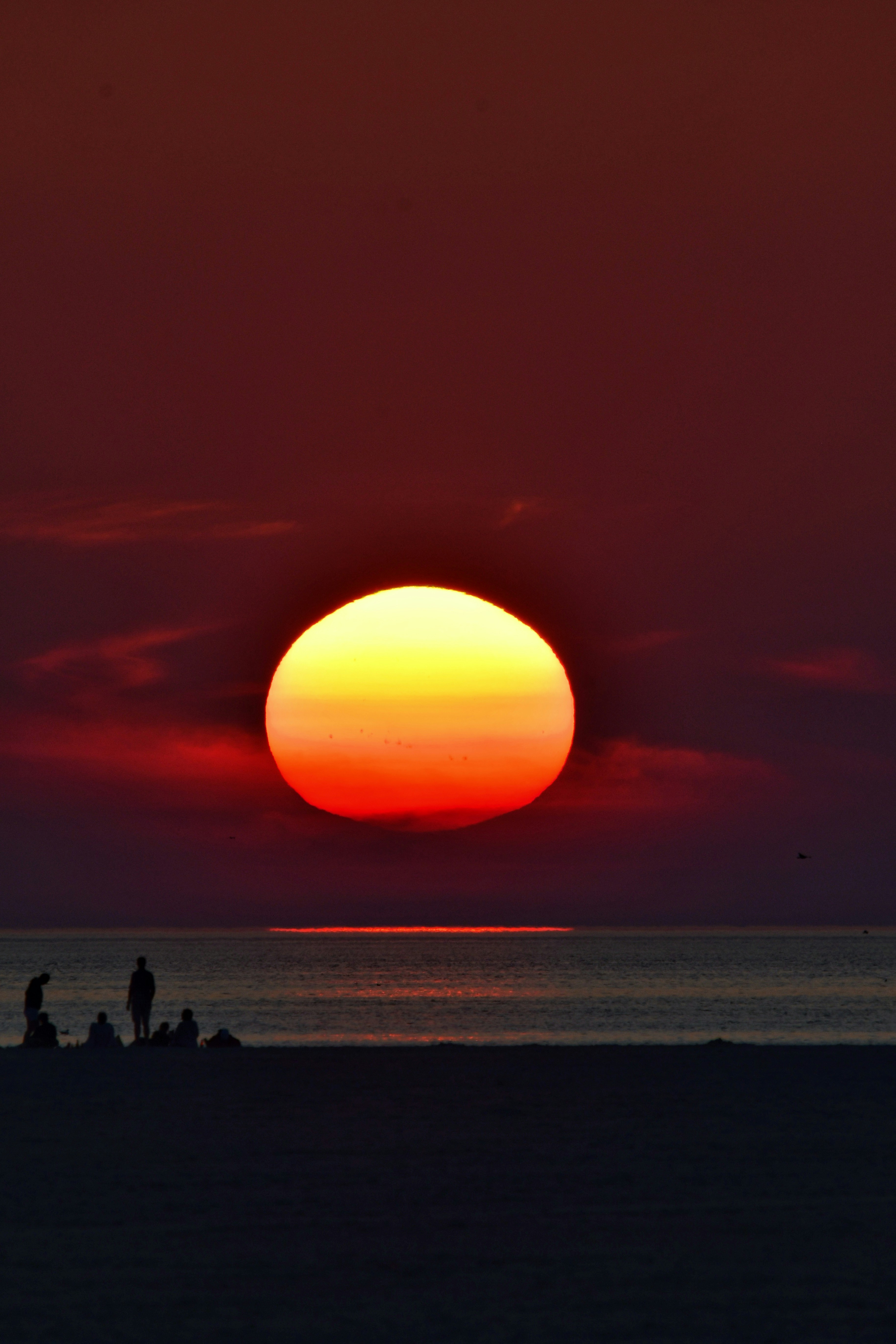 The sun is setting over the ocean on a beach