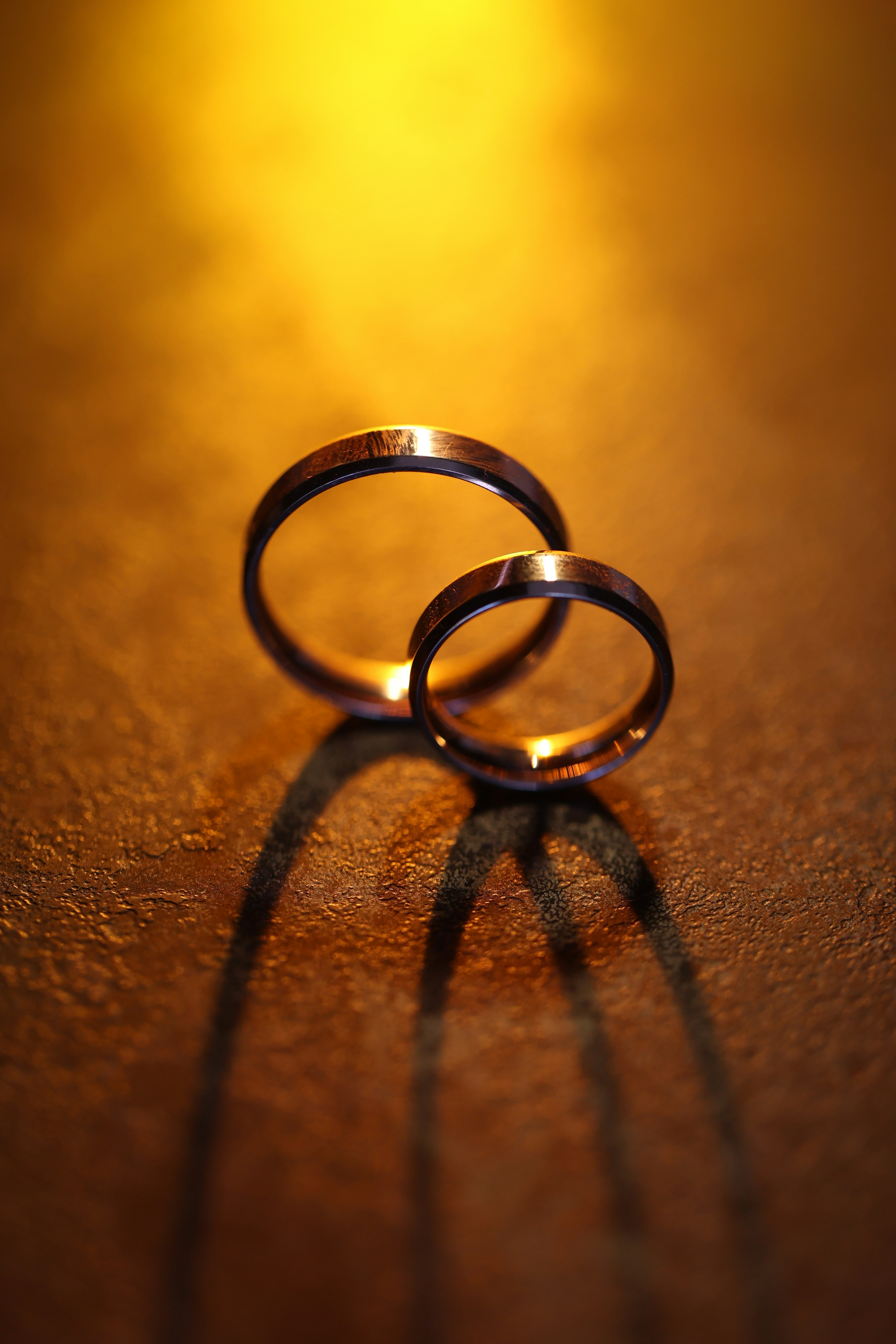 Two wedding rings casting a shadow on a table
