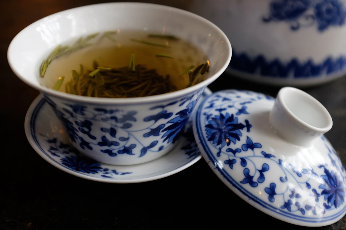 Ceramic cup of green tea near a traditional teapot