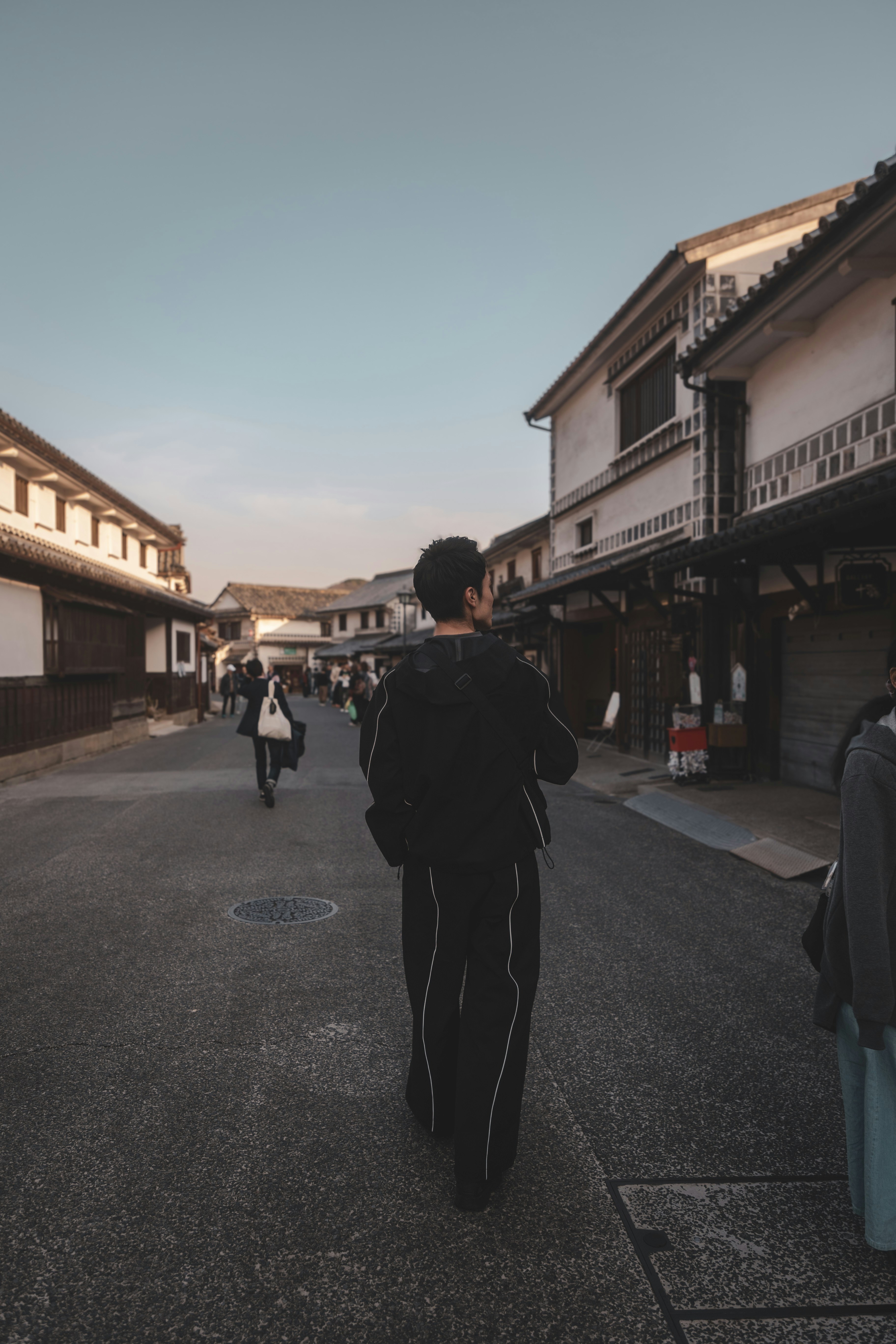 A man walking down a street next to tall buildings