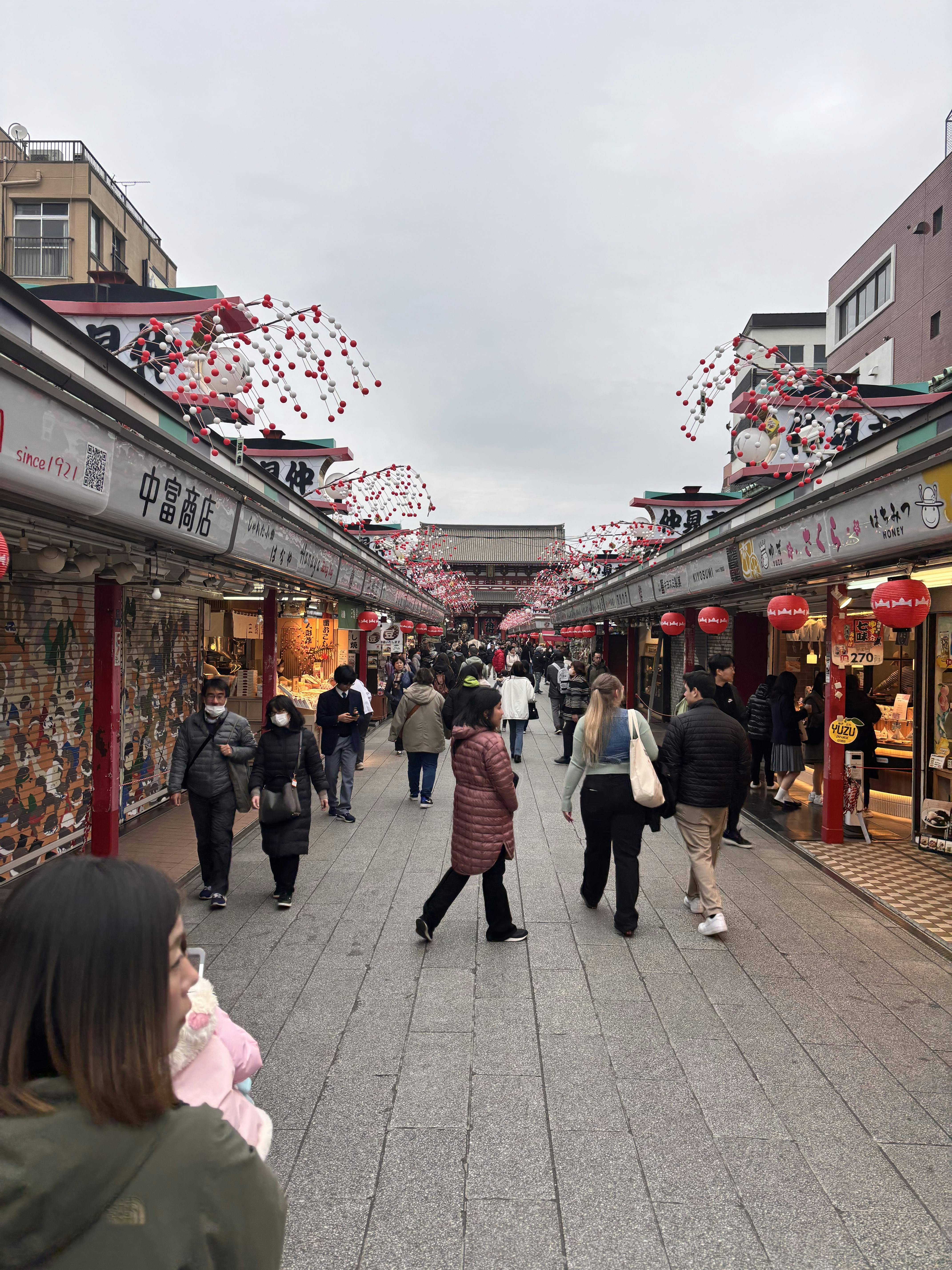 A group of people walking down a street next to shops