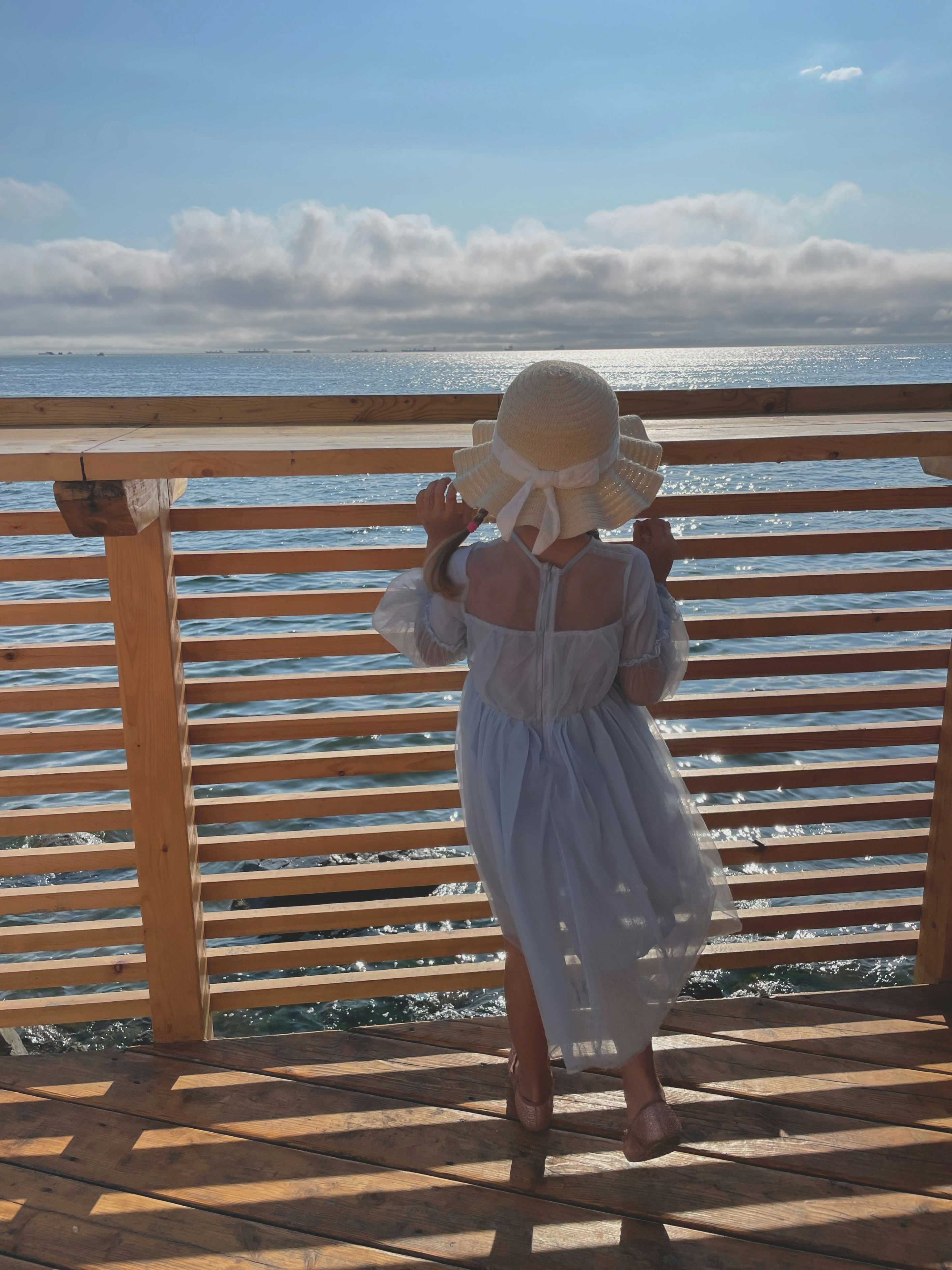 Ein kleines Mädchen trägt ein weißes Kleid und einen weißen Hut