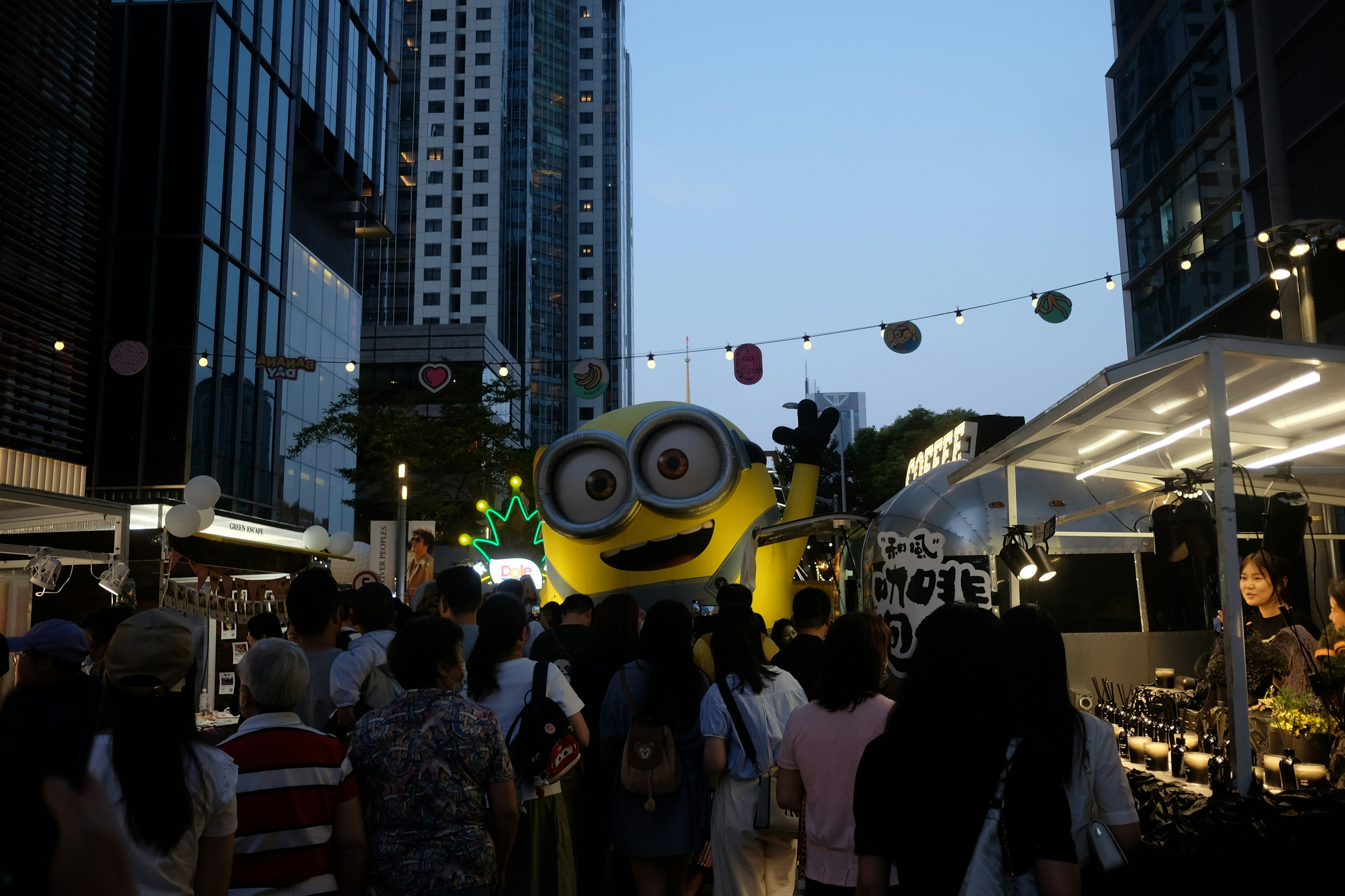 A group of people walking down a street next to tall buildings
