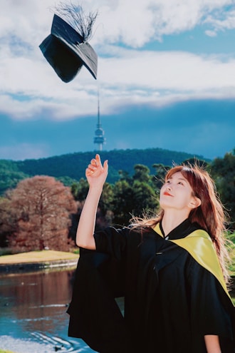 A woman in a graduation gown throwing a hat into the air