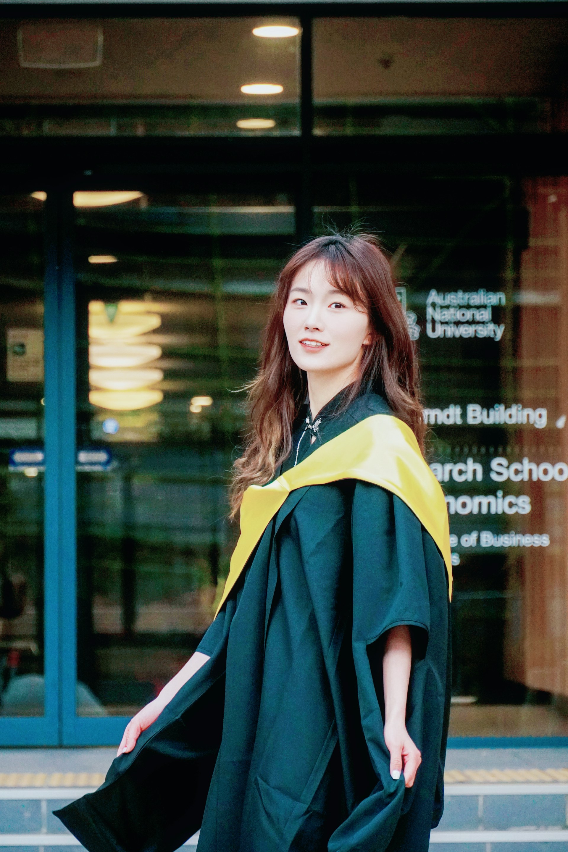 A woman in a graduation gown standing outside of a building