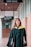 A woman in a graduation gown is walking down a hallway