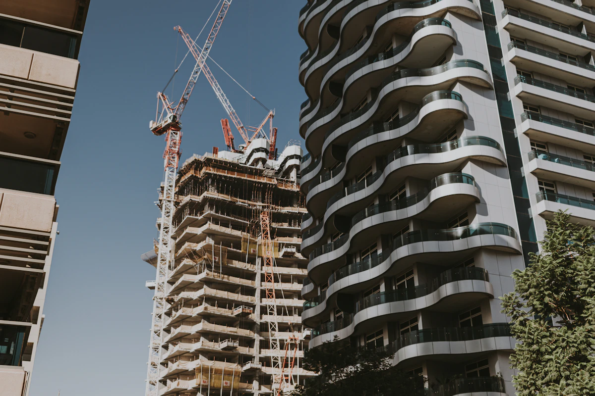 Pembangunan gedung tinggi dengan derek di samping apartemen modern