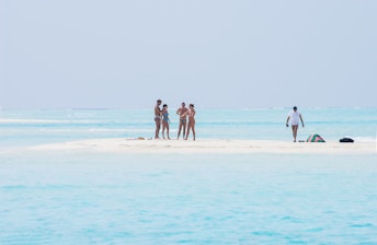 A group of people standing on a small island in the middle of the ocean