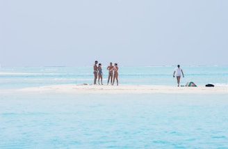 A group of people standing on a small island in the middle of the ocean