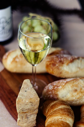 A table topped with croissants and a glass of wine