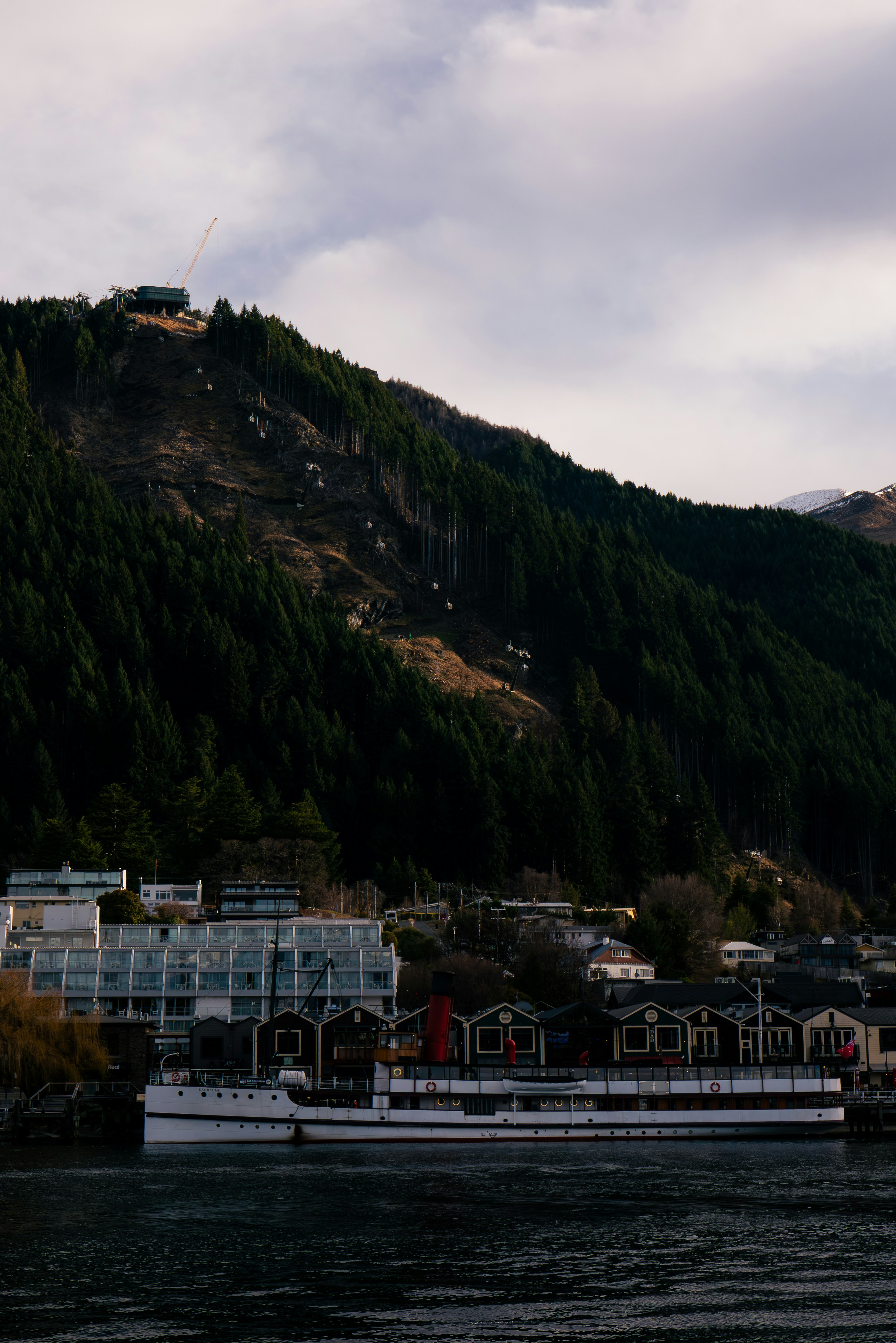 A boat floating on top of a lake next to a mountain