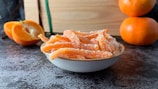 A bowl filled with orange peels next to a book