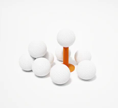 A group of white golf balls sitting on top of an orange tee