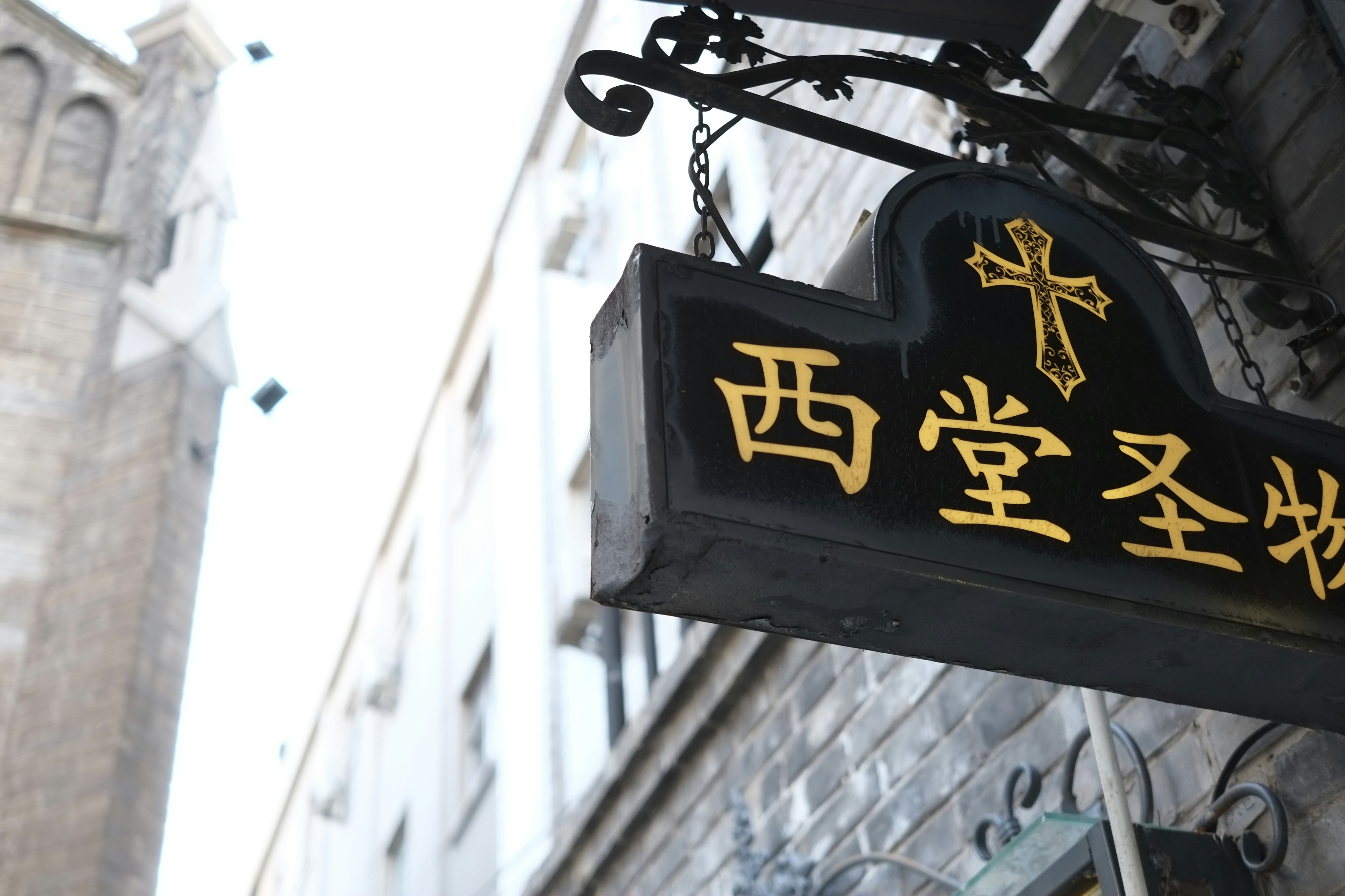 A black and gold sign hanging from the side of a building