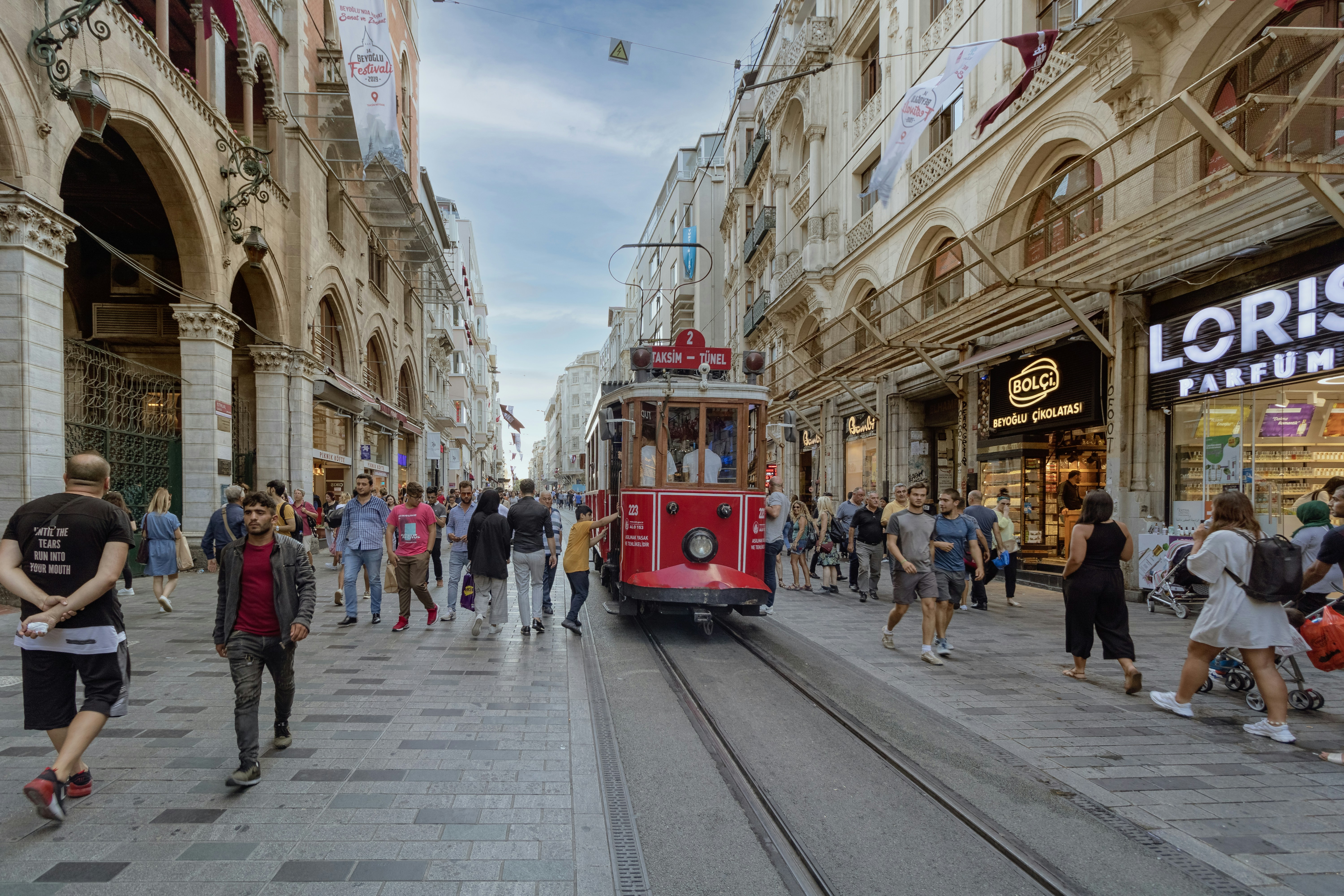 A red trolley car traveling down a street next to tall buildings