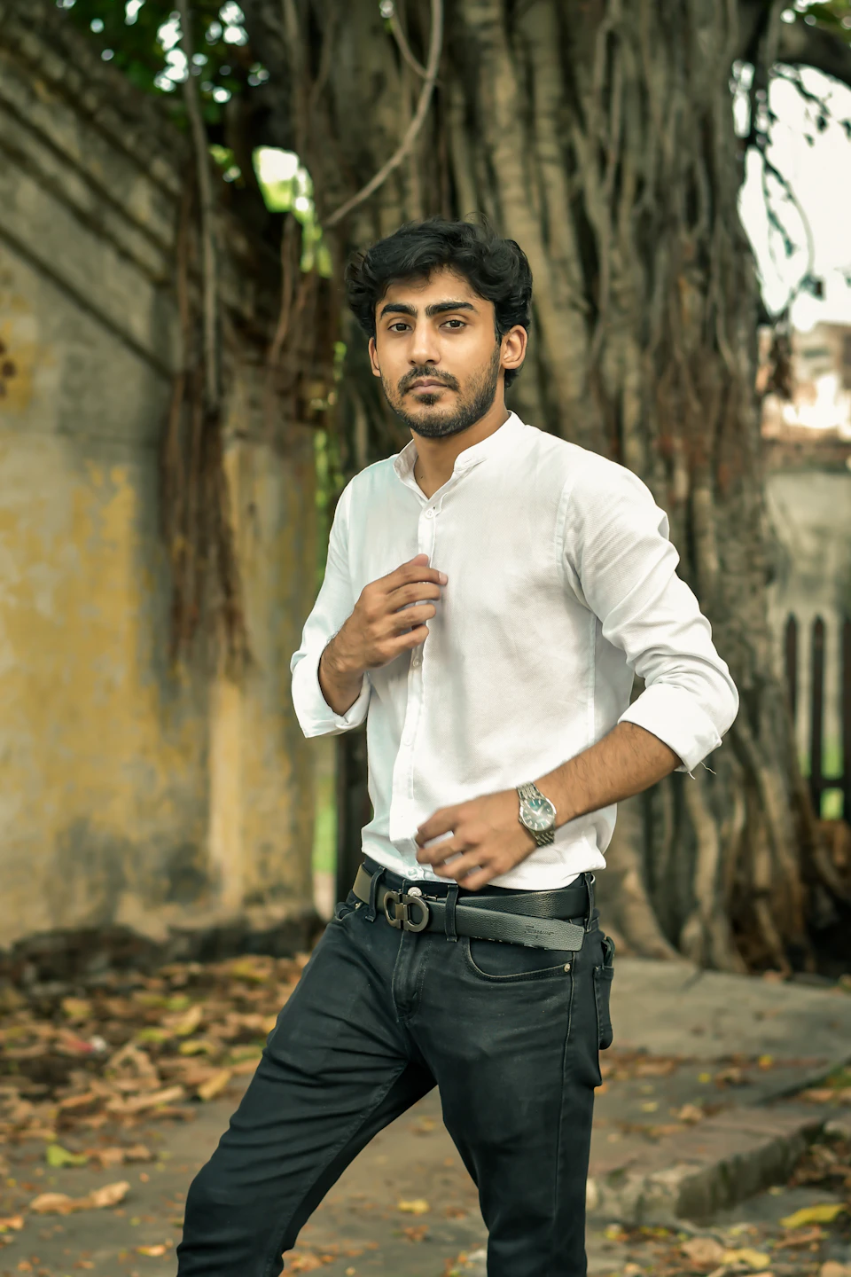 Young man standing on sidewalk with watch on left wrist and hand on hip