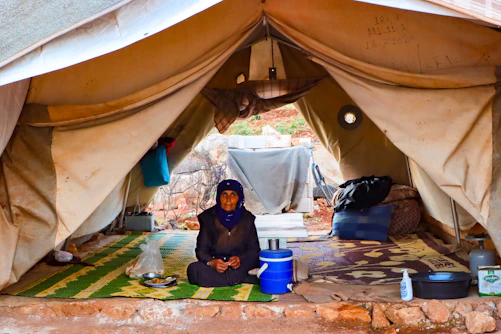 A person sitting on a rug in a tent