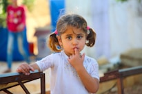 A little girl standing next to a wooden bench