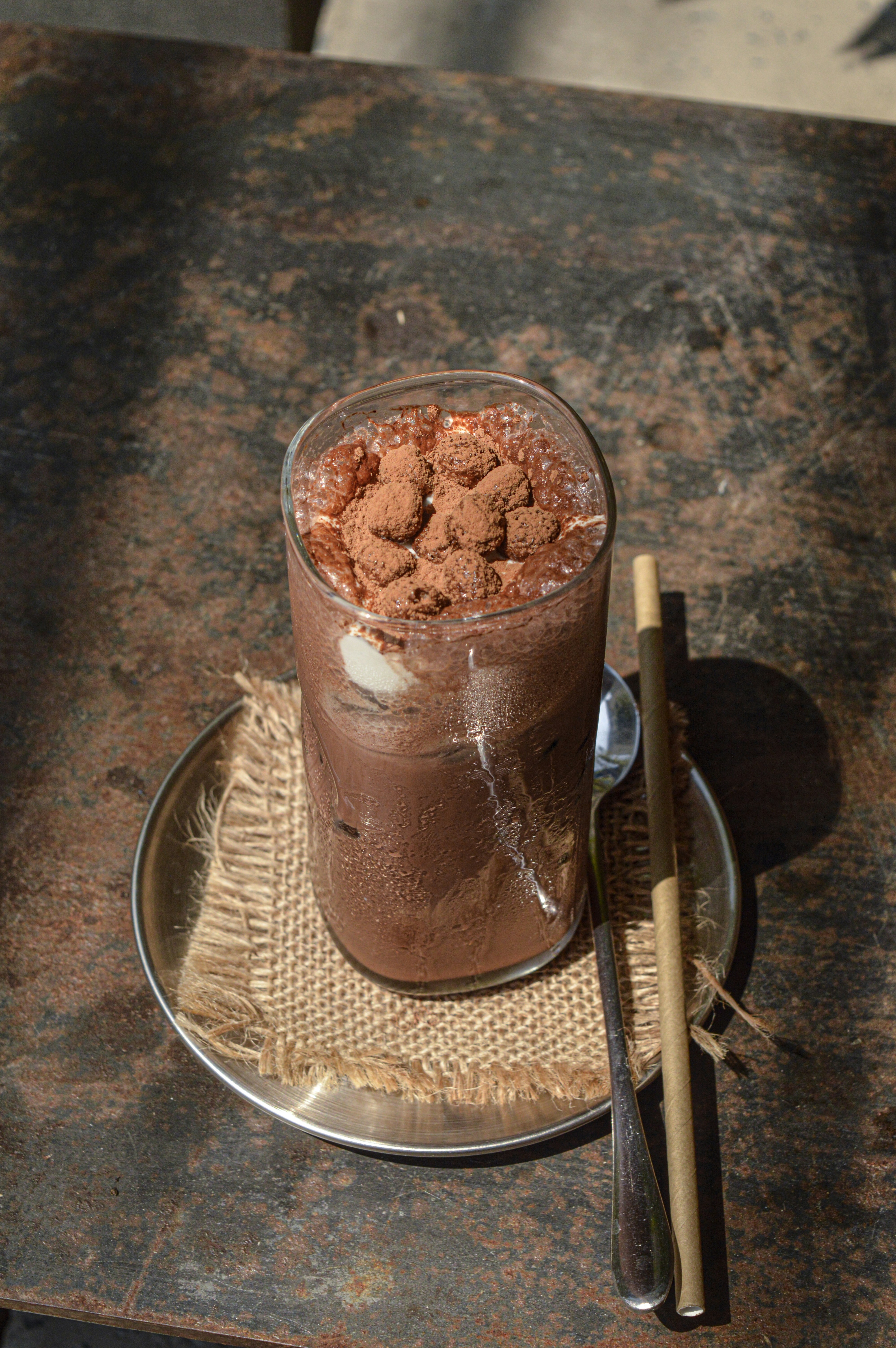 A glass of chocolate pudding on a plate with a spoon