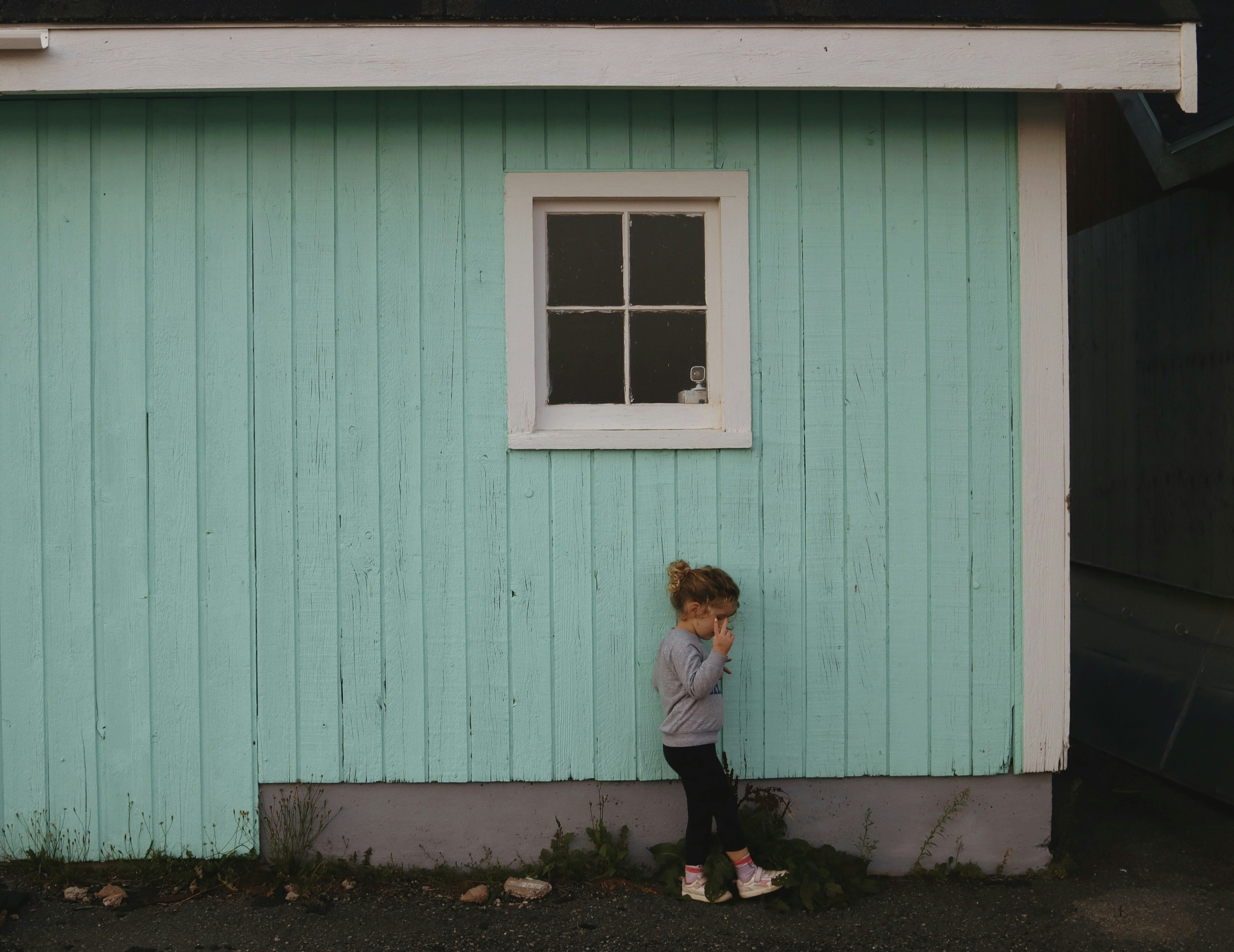 A little girl standing in front of a blue house