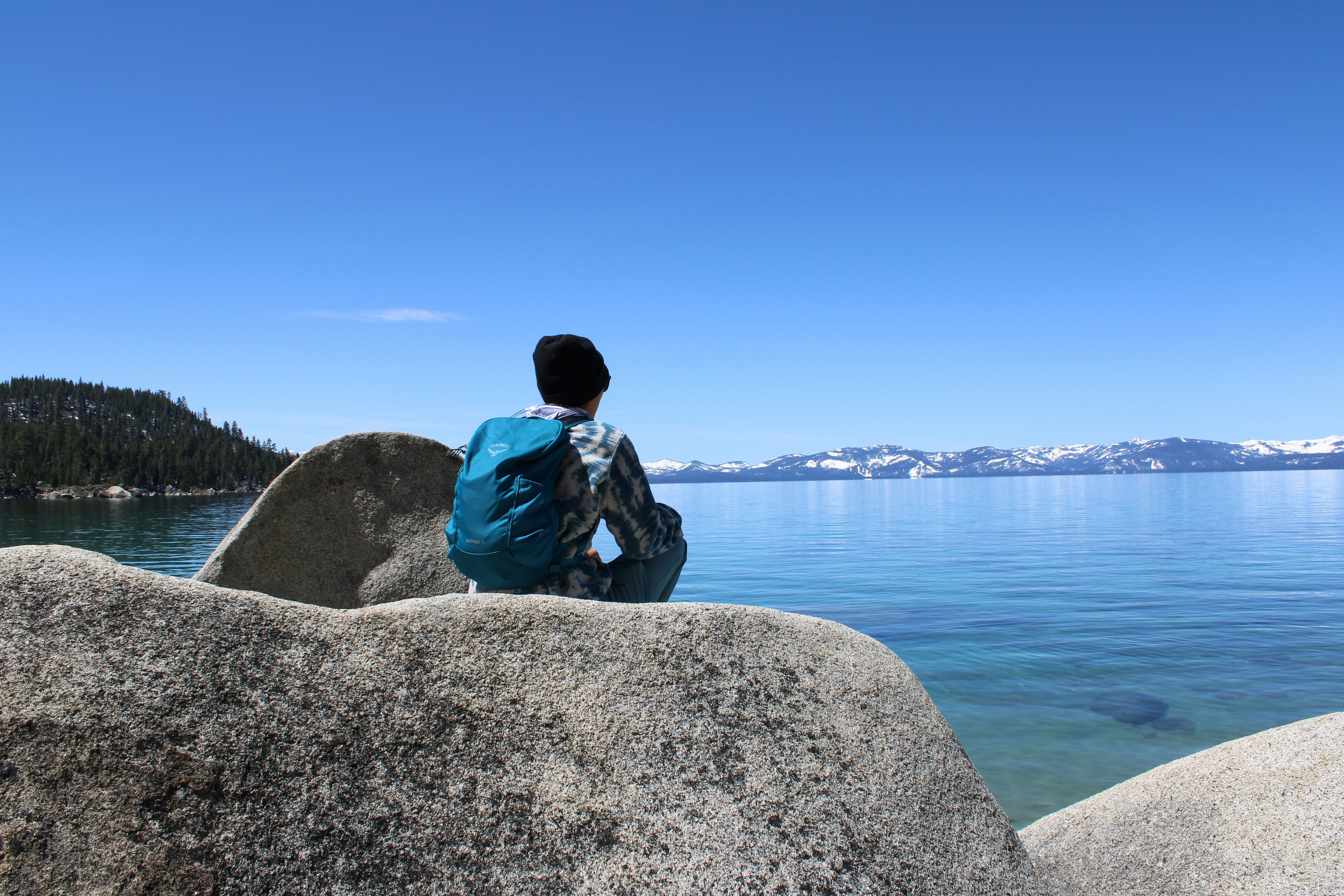 A person sitting on a rock looking out at the water