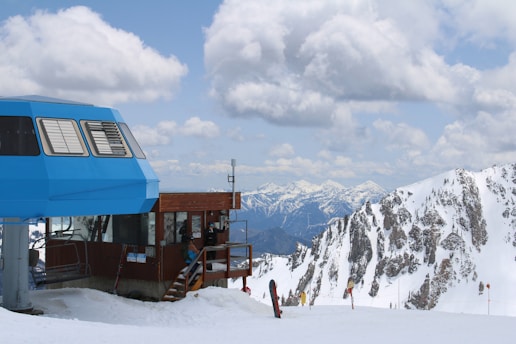 A blue bus parked on top of a snow covered slope