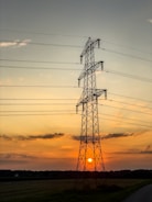 The sun is setting behind the power lines