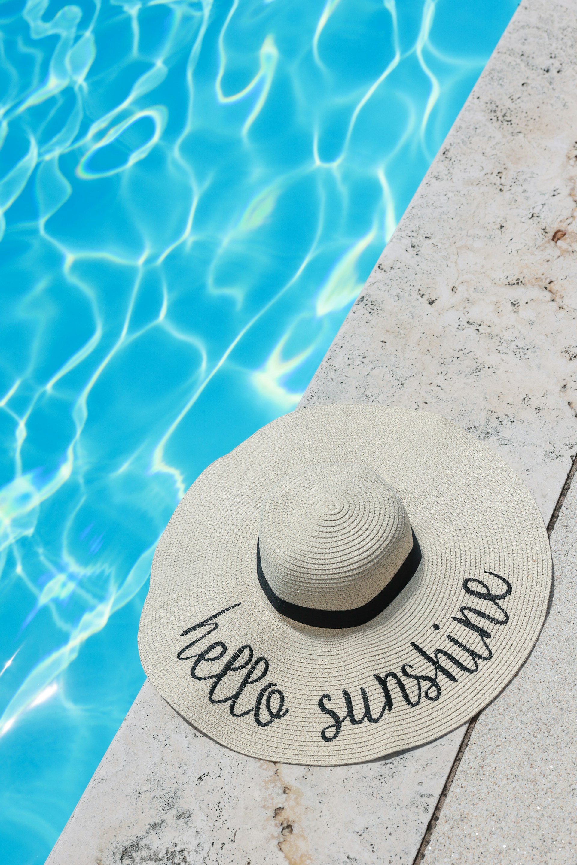 A hat sitting on the edge of a swimming pool