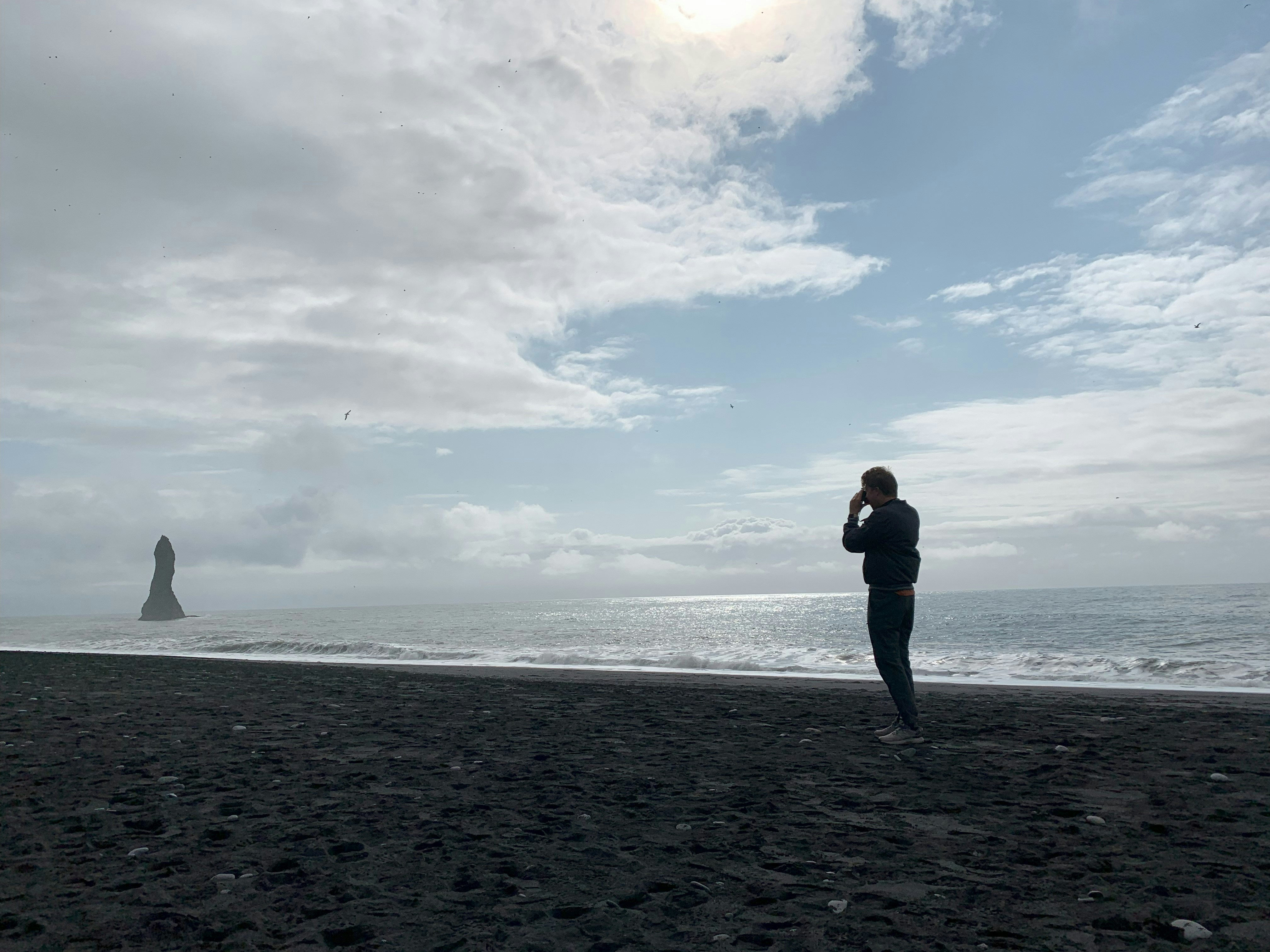 A man standing on top of a beach next to the ocean