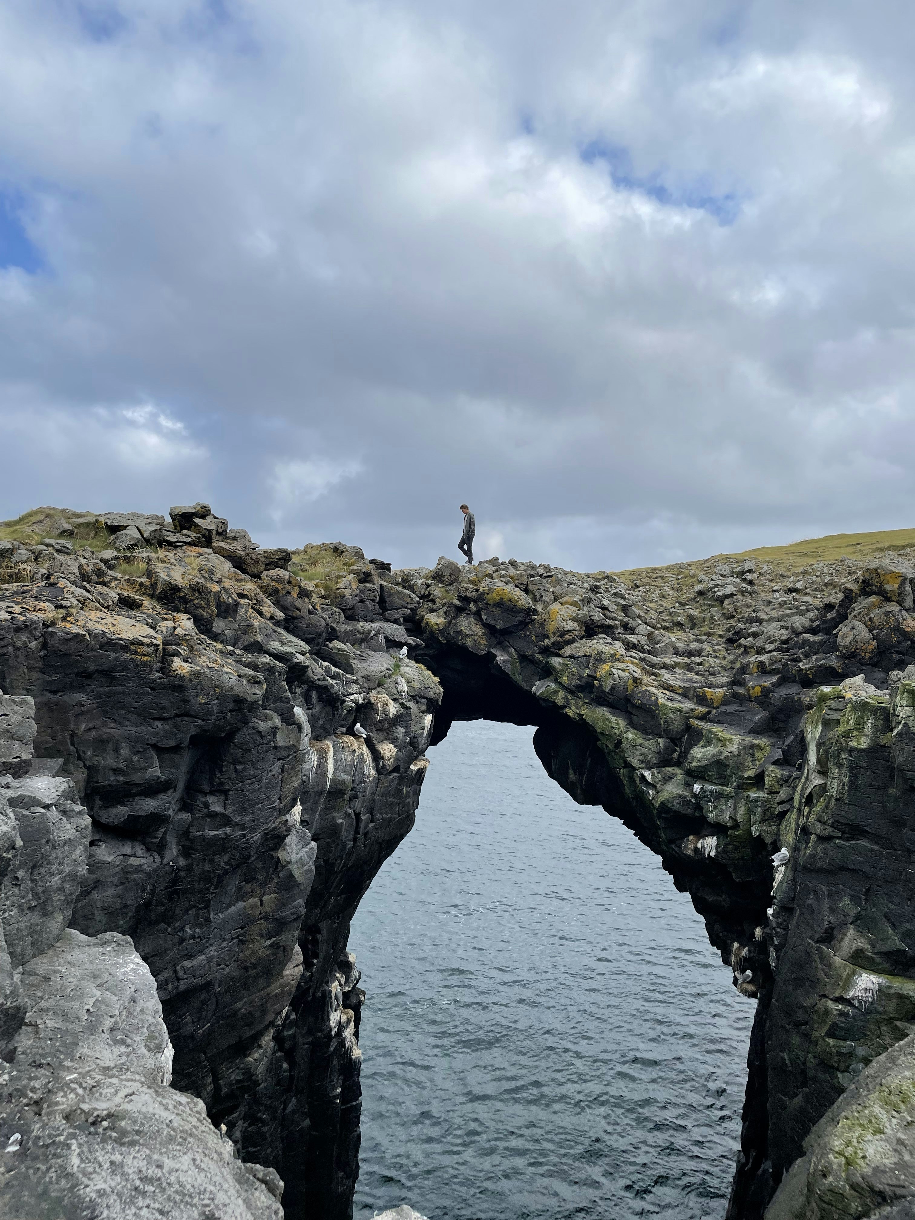 A person standing on a rock bridge over a body of water
