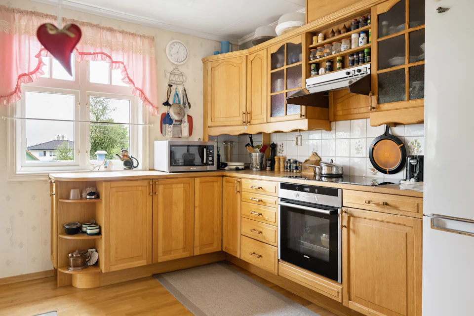 Cozy kitchen with warm colors, wooden cabinets, and appliances against a sunny backdrop