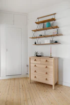A white room with a wooden dresser and shelves