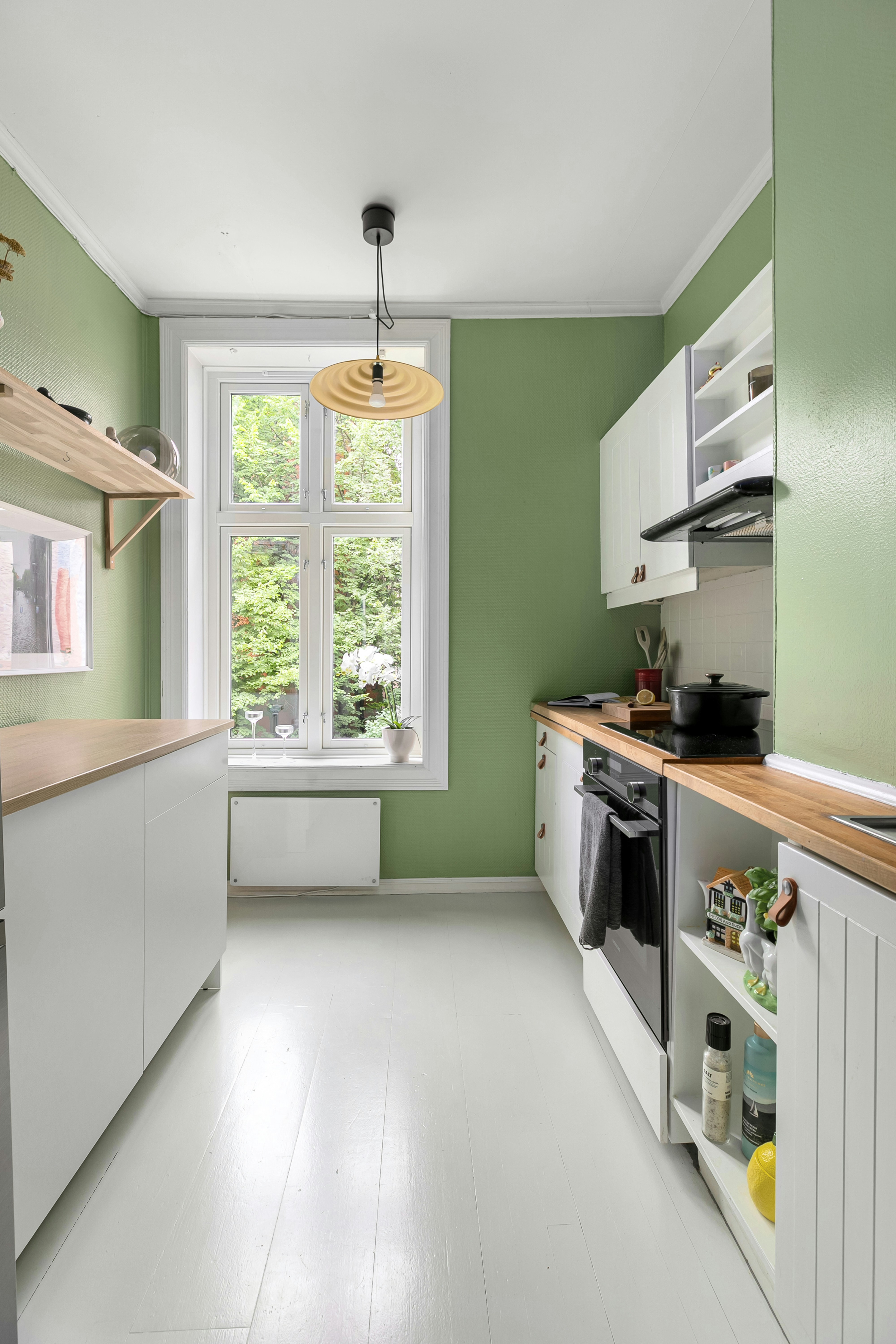 A kitchen with green walls and white cabinets