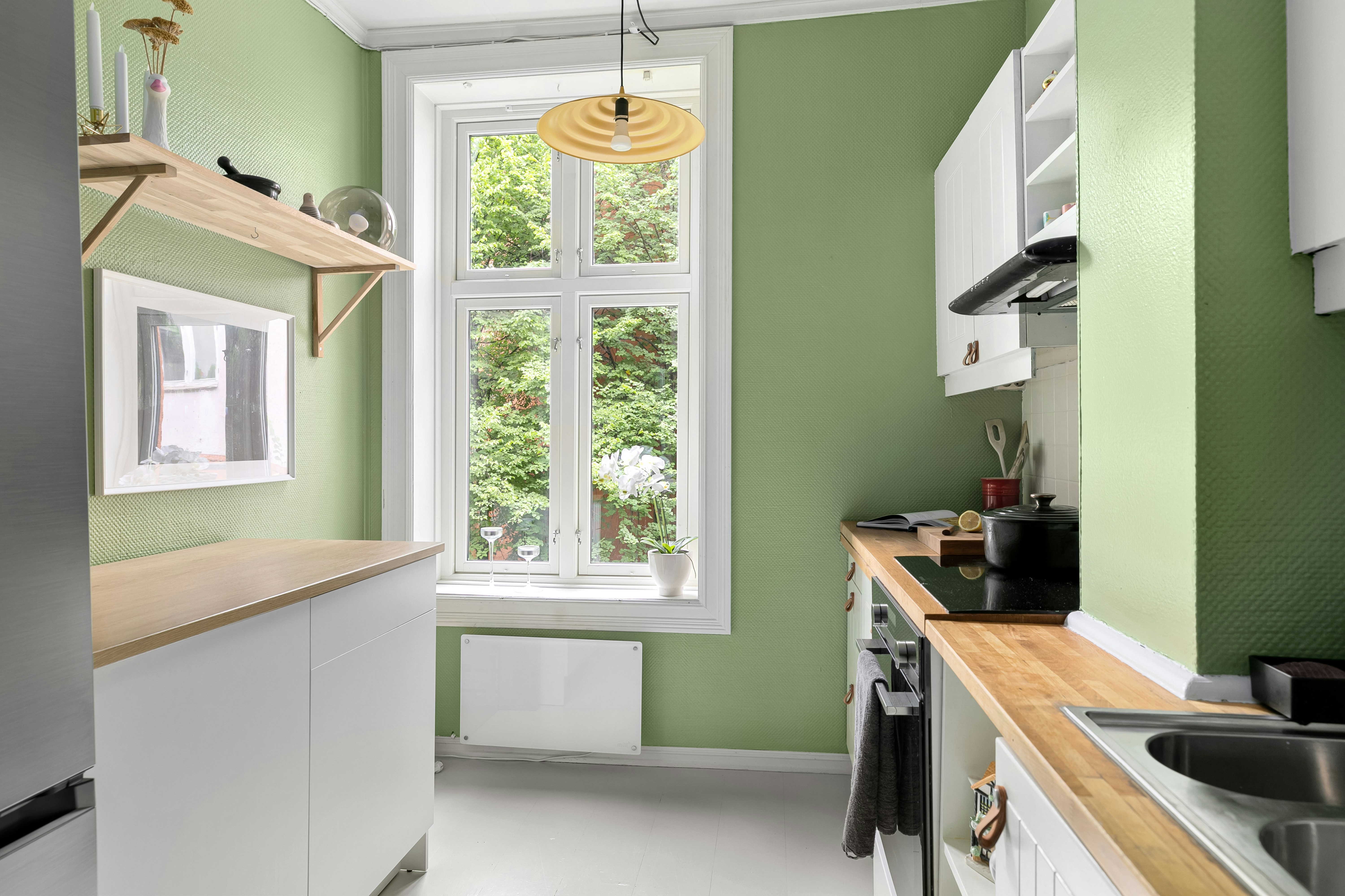 A kitchen with green walls and white cabinets